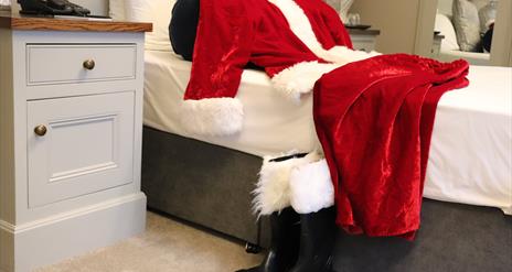 Santa's red suit and boots on a bed at The Causeway Hotel