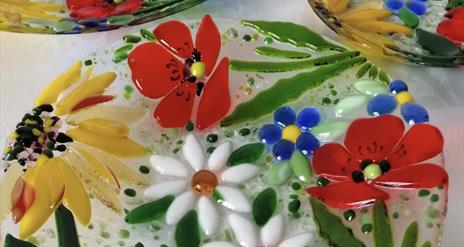 A glass plate decorated with colourful glass flowers.