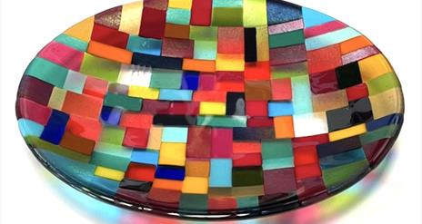 A shallow glass dish made from various different colours arranged in geometric patterns.