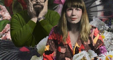 Rachel McCarthy and Michael Keeney post in front of a colourful background of flowers and patterns.