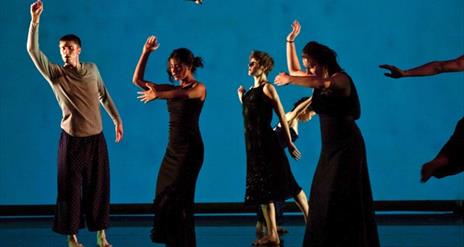 Dancers performing in front of a blue screen.