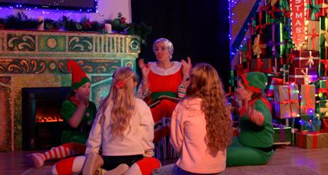 Mrs Claus presenting the story of Christmas as children and elves watch on as part of the Christmas by the Coast Portstewart Magical Experience