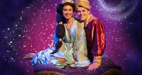 characters Jasmine and Aladdin sit on their magic carpet against a sparkly purple background