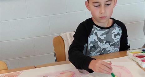 a child painting with a large paint brush.