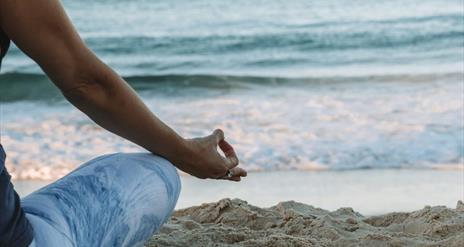 A person sitting in a relaxing pose at a beach with an ocean view