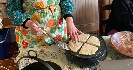 person in a apron bakes bread on a griddle pan