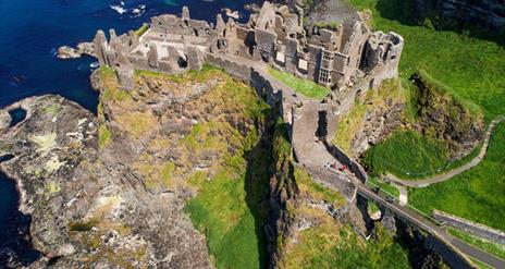 The ruins of Dunluce Castle perched on the edge of a cliff with the sea below