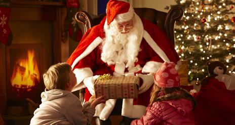 Santa claus giving a present to two children