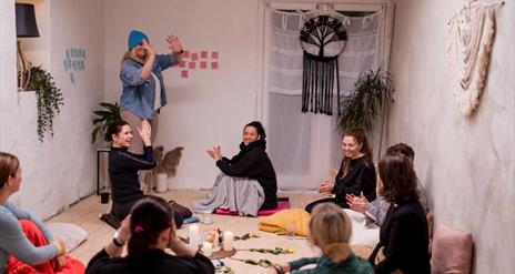 group of women in a room talking and joing their palms together