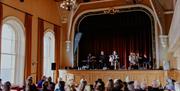 a band performs on stage at Portrush Town Hall while seated crowds watch