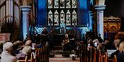 two men playing guitars in a church onstage at Atlantic Sessions