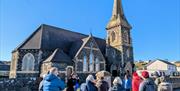 Bob Picken guiding a group dressed in outdoor clothing learning about the village of Castlerockclothing and hearing stories of the Earl Bishop