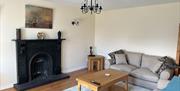 Bright living room featuring a cream corner sofa, wooden coffee table and a black decorative fireplace with mantelpiece.