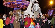 Image shows a group of people standing in front of scary Halloween characters, with a Fairground in the background