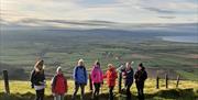 a group of people have their photo taken atop Binevenagh Mountain