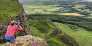 a person takes a photo of the view from Binevenagh Mountain