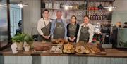 Staff from Bistro at the Courthouse stand behind the restaurants counter, with plenty of bakes and sweet treats in front of them