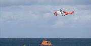 a rescue boat cruises in the ocean while an air ambulance helicopter hovers above