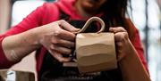 a potter hand sculpting a mug