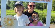 two children smile with a woman wearing sunglasses