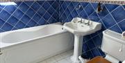 Family bathroom with a bath, pedestal sink and blue tiled walls.