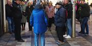 people gathered on the street listening to Francis as he leads a tour