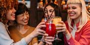 a group of women raise glasses of cocktails together
