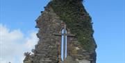 Ruins of old Church with Cross and ivy growing down the side of the ruins.