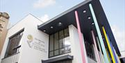 Photo of the front of the building. Windows and white walls with large 'R' logo and text reading "Roe Valley Arts and Cultural Centre". There are also