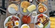 A table set with four places showing cooked breakfasts and other brunch items