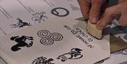 a pair of hands press an ink print stamp into a small fabric banner