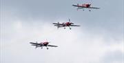 three red and white planes flying together through the sky