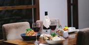 a table is set with plated dishes and glasses of red wine