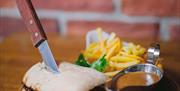 a plated steak ciabatta with a side of sauce and fries