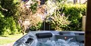 Image of the hot tub at the rear of the garden with a robe