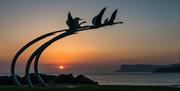 children of lir sculpture in Ballycastle at sunset