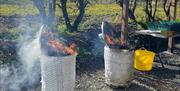 smoke rises from two barrels that are being used to fire pots