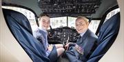 Military service women sit inside an aircraft cockpit