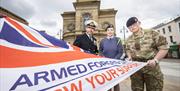 Military service men and women hold an Armed Forces Flag
