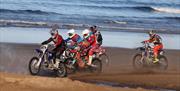 Riders on the sand with waves in the background