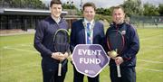The organisers of Country Antrim Tennis Championships stand holding rackets and an 'Event Fund' board.