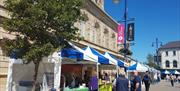 people browsing outdoor market stall tents on a sunny day