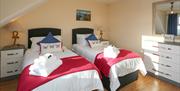 Carrick-a-Rede Rope Bridge Bedroom with two single beds, a chest of drawers and a mirror.