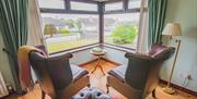 Seating area with 2 armchairs positioned by a bay window.