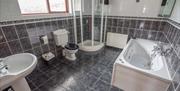 Tiled main bathroom with sink, toilet, corner shower, and jacuzzi bath.