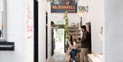 a woman sits on the steps at House of McDonnell while talking to a man who is standing, they are both holding drinks