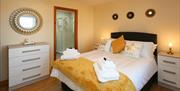 Dunluce Castle Bedroom with a double bed, chest of drawers and a door to an en-suite.