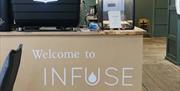 sign on a cafe counter reads 'Welcome to INFUSE'