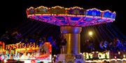 Image shows children enjoying the brightly lit up fairground rides