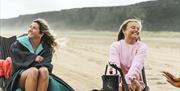Two ladies relax by a fire pit on the beach